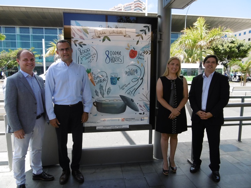 Autoridades de Metrotenerife, Universidad Europea de Canarias, Mutua de Accidentes de Canarias y Publiservic posan uno de los carteles en la parada Intercambiador de Santa Cruz. 