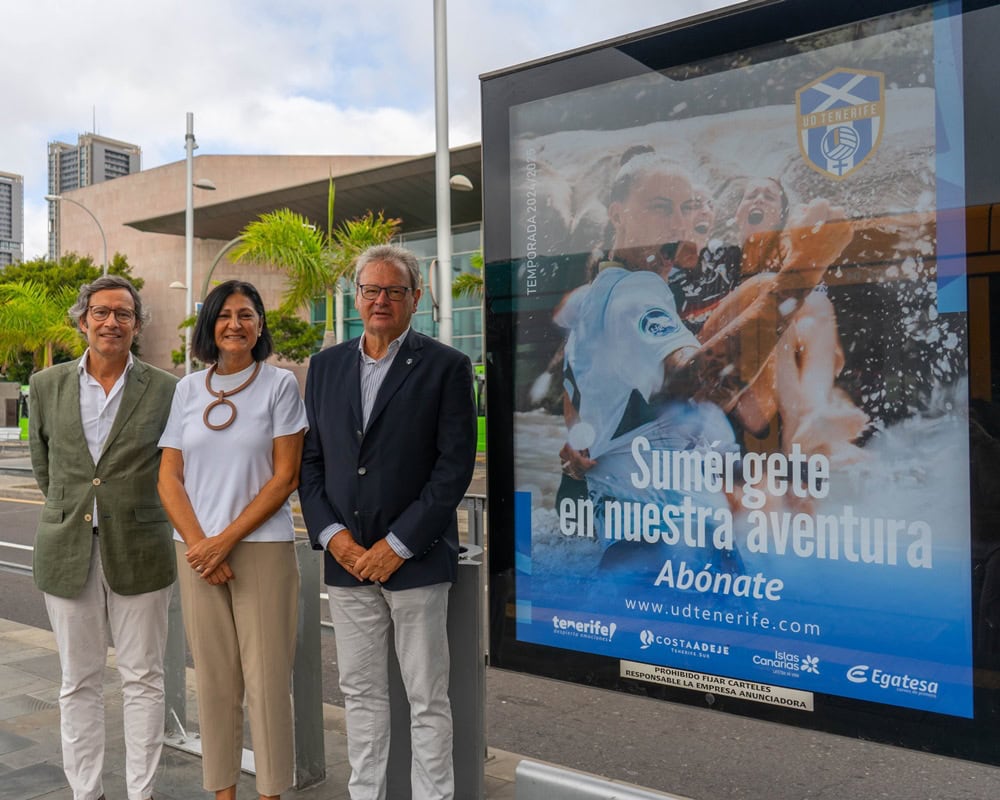 Autoridades del Cabildo de Tenerife, Metroteneife y UD Tenerife junto a la imagen de la campaña en una parada del tranvía. 